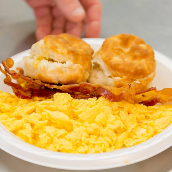A plate of scrambled eggs, crispy bacon, and two golden biscuits from Druther's Restaurant.