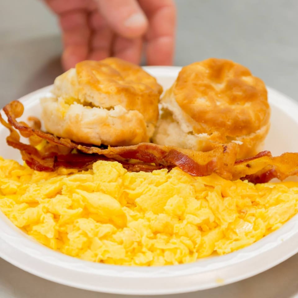 A plate of scrambled eggs, crispy bacon, and two golden biscuits from Druther's Restaurant.