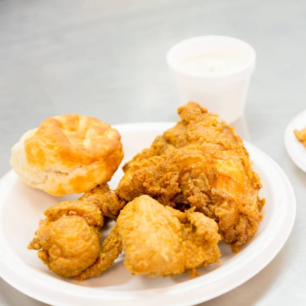 A plate of Druther's crispy fried chicken and a biscuit, with a drink in the background.